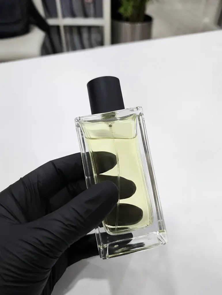 Hands holding plain glass perfume bottles filled with fragrances, representing fully customizable private label perfume options at 3F Perfumes UAE.